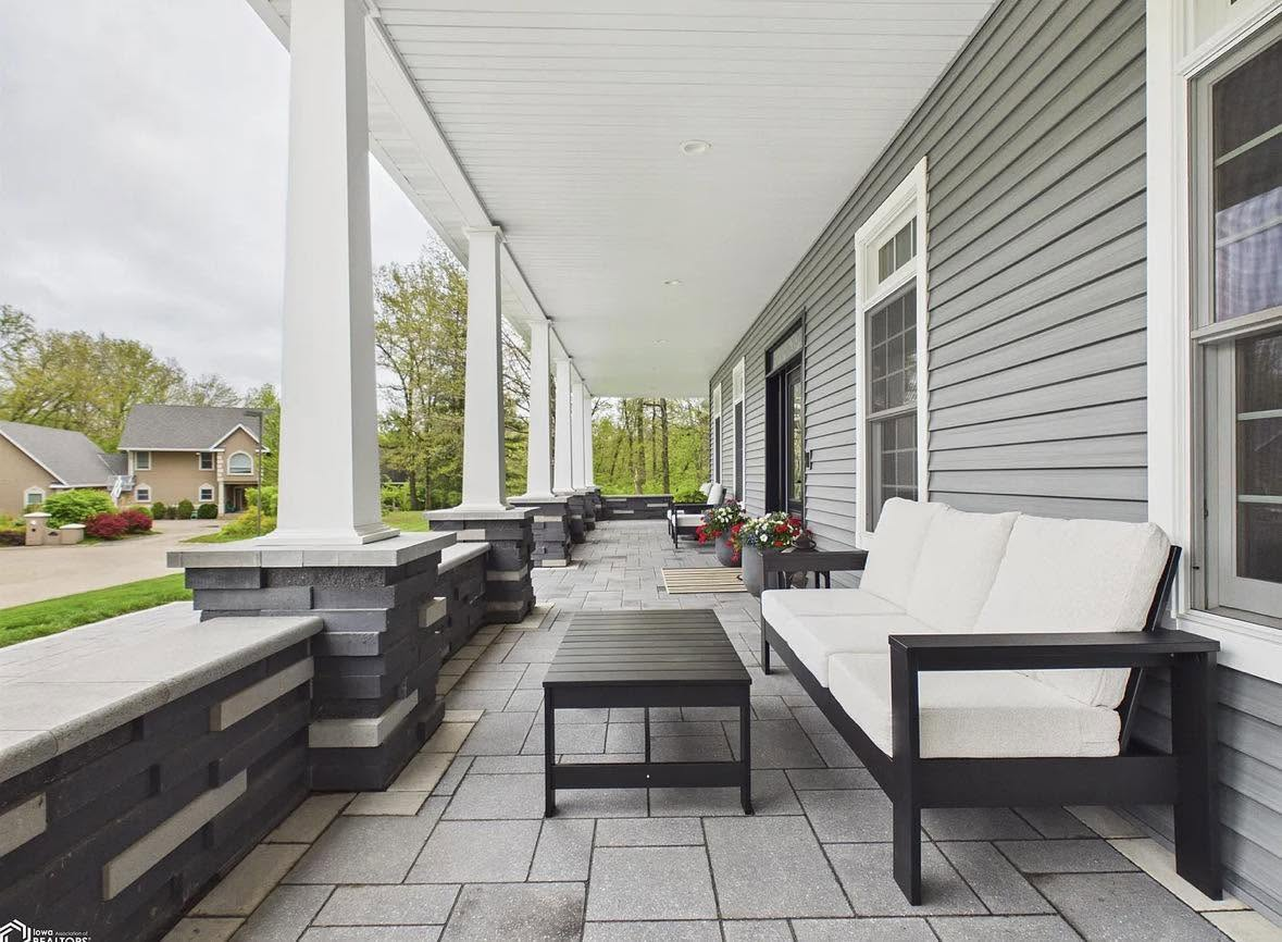 Freshly cleaned covered front porch with stone pillars and paver floor