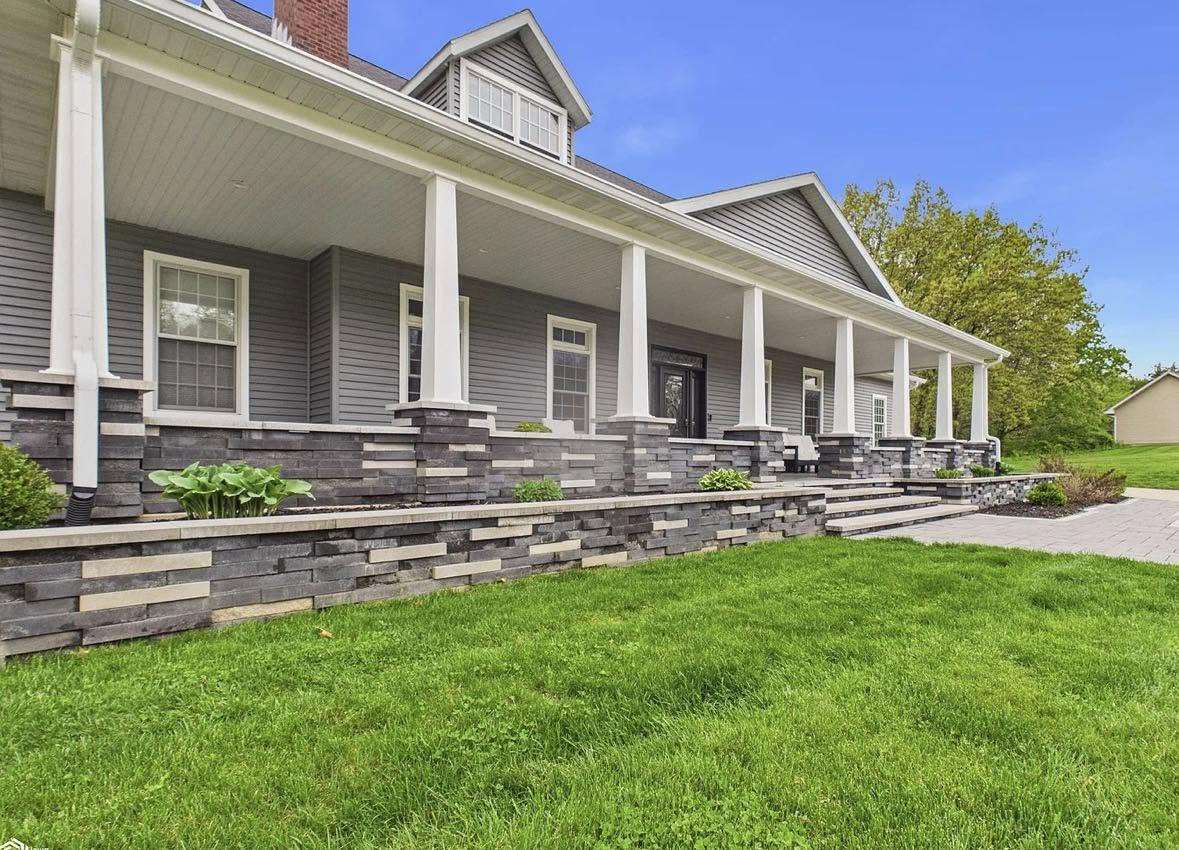 Cleaned grey siding and stone front porch with fresh lawn