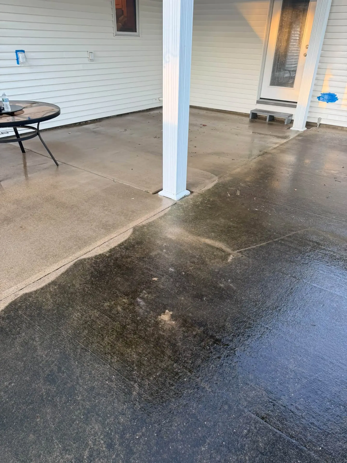Concrete patio being power washed, half clean and half grimy
